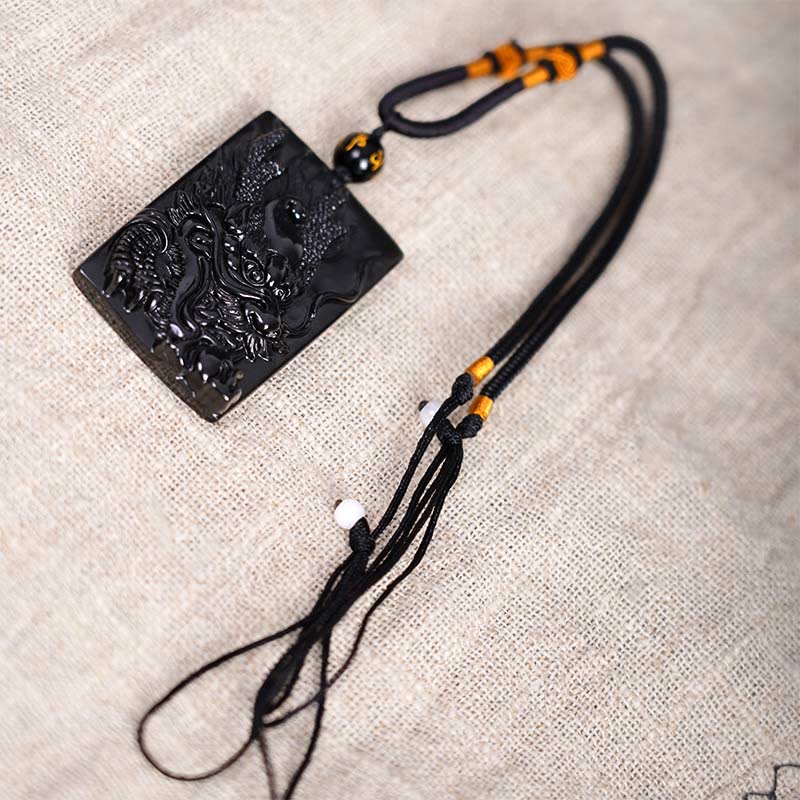 Black Obsidian Dragon Pendant – full dragon body with gold knot cord on driftwood, majestic
