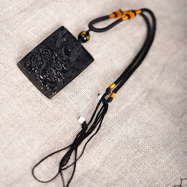 Black Obsidian Dragon Pendant – full dragon body with gold knot cord on driftwood, majestic
