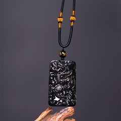 Black Obsidian Dragon Pendant – front view with gold knot cord and inscribed bead on driftwood, confident