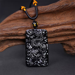 Black Obsidian Dragon Pendant – full dragon body coiled on braided cord with mantra bead on driftwood, auspicious