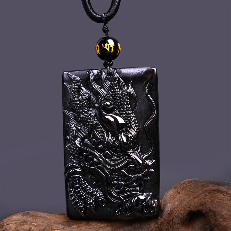 Black Obsidian Dragon Pendant – three-quarter coiled dragon plaque on gray with wood base, dynamic