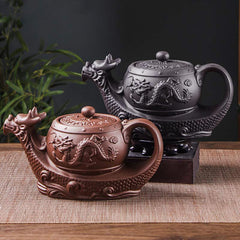 Vintage Dragon Auspicious Clouds Teapot – terracotta and black dragon teapot variants on woven mat with green foliage, craft