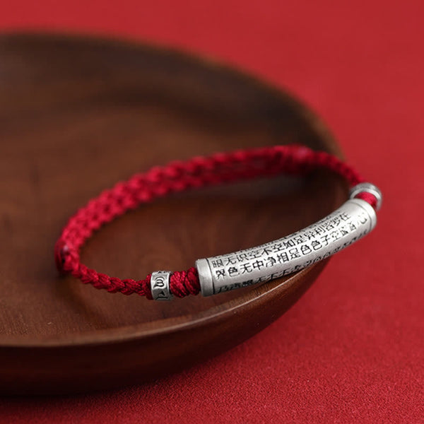 999 Silver Heart Sutra Bracelet – On wooden dish with shallow depth of field, red cord and silver sutra bead, Chinese brac...