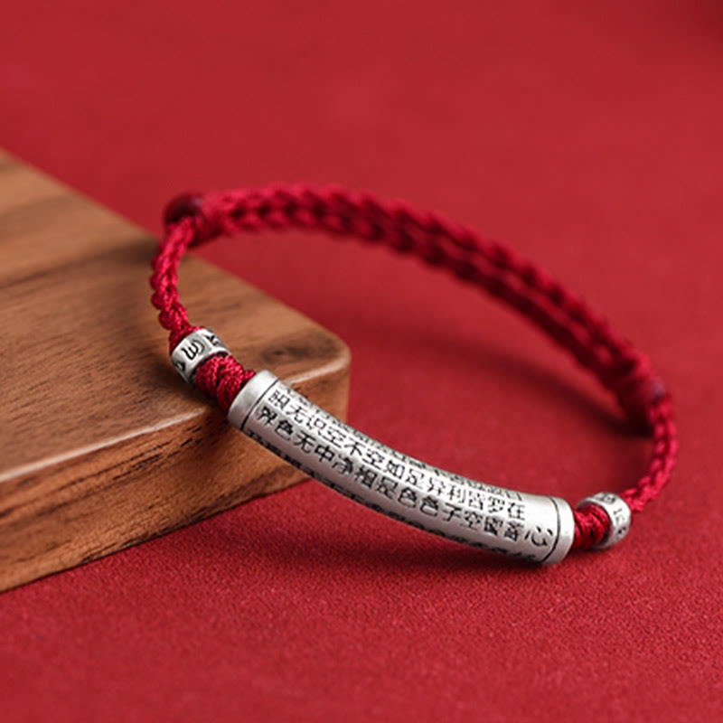 999 Silver Heart Sutra Bracelet – Red cord on wooden prop showing engraved silver charm detail, protection amulet