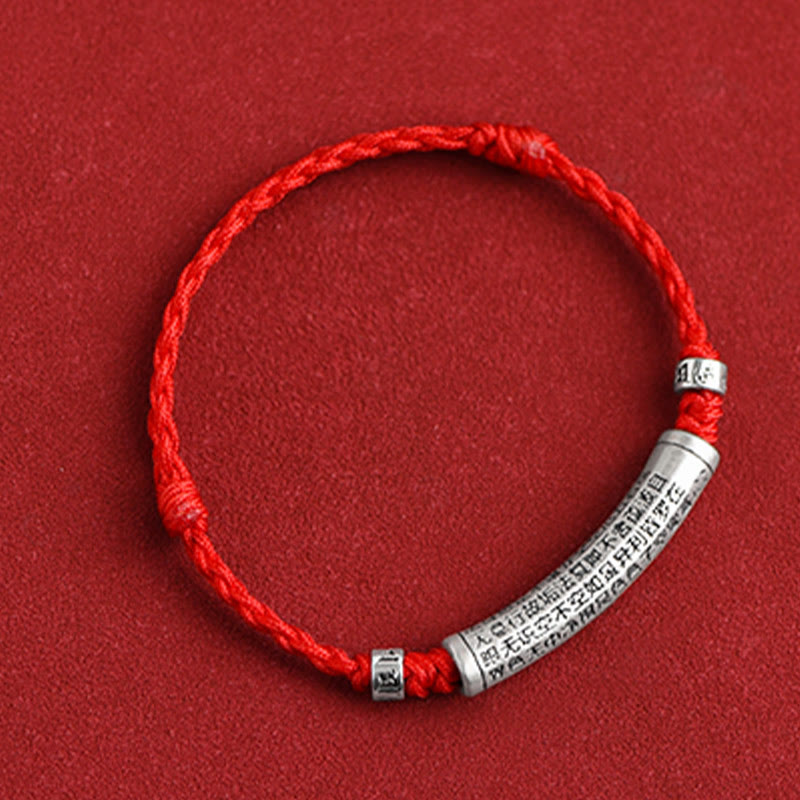 999 Silver Heart Sutra Bracelet – Top-down flat lay on red background with silver mantra cylinder, knotted cord bracelet