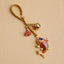 Colorful Koi Fish Hollow Bell Key Chain - blue and red enamel koi with gold braided cord and fortune bell on beige