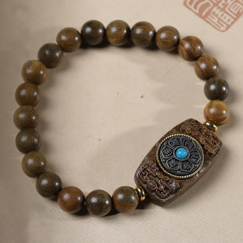 Sandalwood Six True Words Bracelet - Warm brown wood beads with carved mantra centerpiece, flat lay