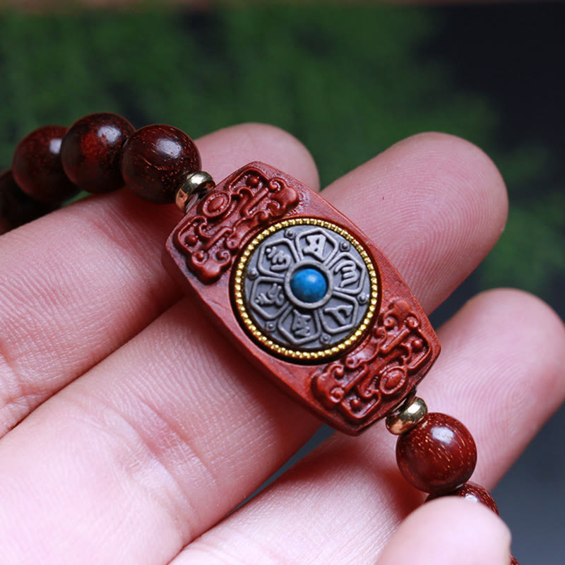 Sandalwood Six True Words Bracelet - Macro detail of carved mantra charm with blue stone center