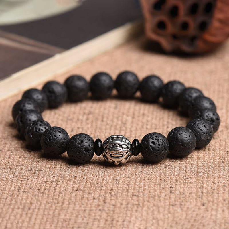 Lava Stone PiXiu Bracelet with carved silver Buddha bead on burlap, book and wood props, spiritual healing