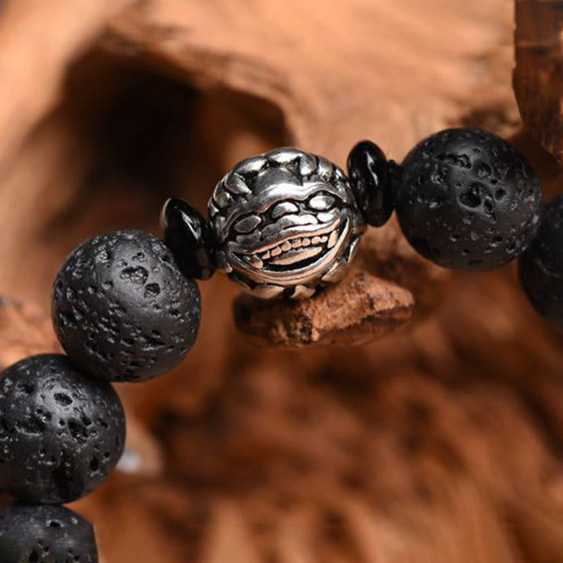 Lava Rock PiXiu Bracelet macro on weathered wood, sculpted silver face bead, volcanic stone texture, artisan