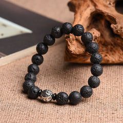 Lava Rock Beads Silver PiXiu Bracelet on driftwood prop, burlap background, rough volcanic stone texture, healing