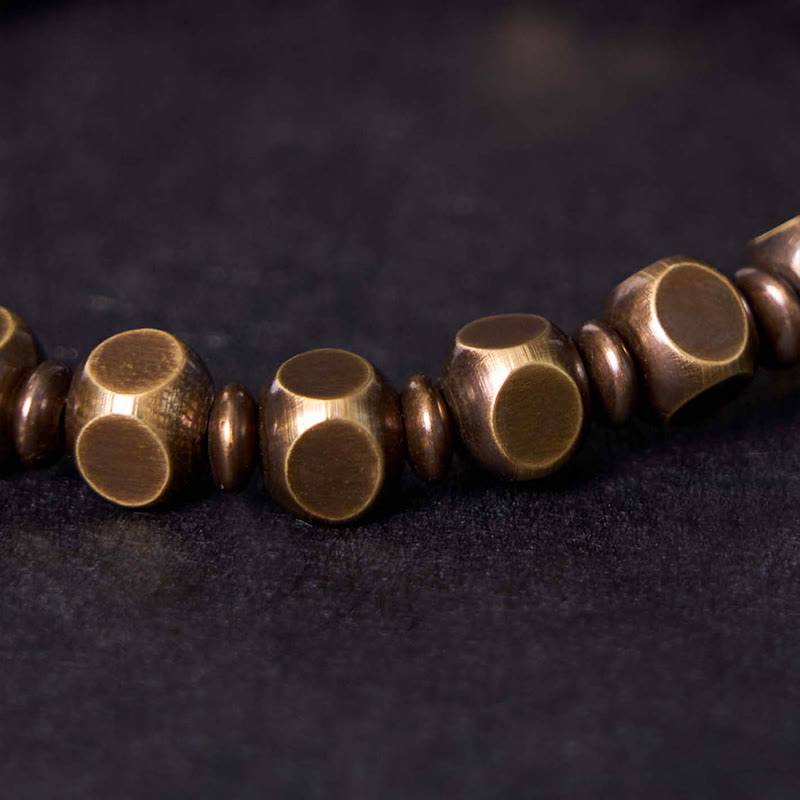Brass Om Mani Padme Hum Bracelet – worn on wrist with dark bokeh background, engraved cylinder bead, men's healing bracelet