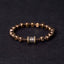 Om Mani Padme Hum Brass Bracelet - Brass hexagonal beads with prayer wheel focal, dark backdrop, men spiritual
