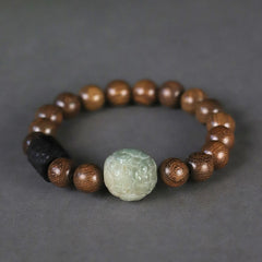 Sandalwood Bodhi PiXiu Bracelet on gray background, pale green jade carving, black cylindrical bead, healing