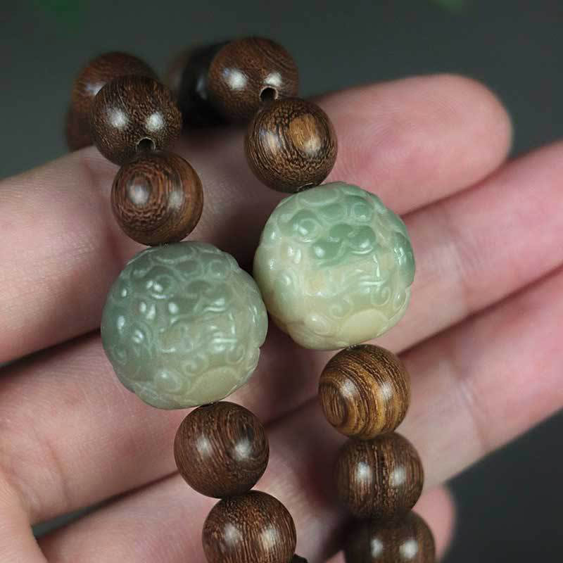 Sandalwood PiXiu Bracelet worn on hand, carved jade mythical beast beads, dark background, healing jewelry