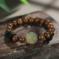 Wood Bead Jade PiXiu Bracelet on rustic stone, carved celadon jade center, dark accent bead, meditation mala