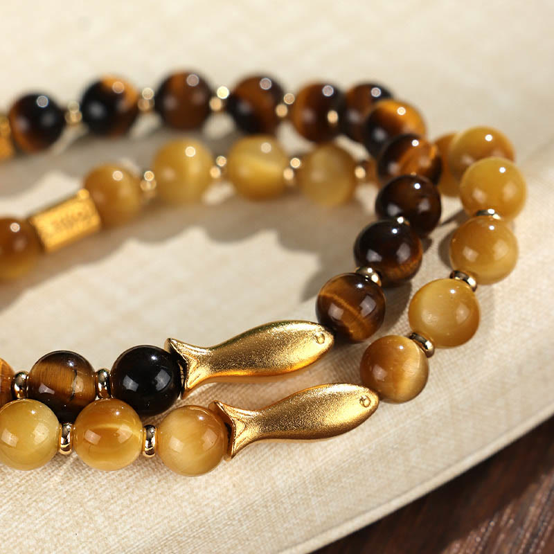 Tiger Eye Koi Fish Courage Bracelet – two bracelets with gold fish charms on linen, close-up selective focus