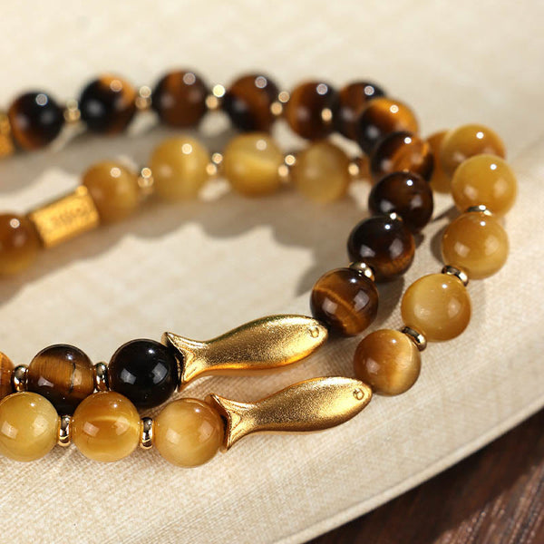 Tiger Eye Koi Fish Courage Bracelet – two bracelets with gold fish charms on linen, close-up selective focus