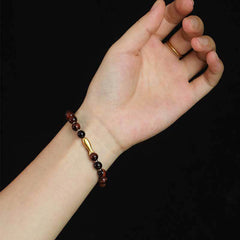 Tiger Eye Koi Fish Courage Bracelet – red tiger eye with gold fish charm on wrist against black background