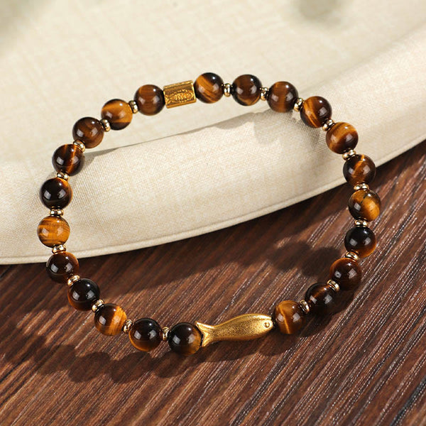 Tiger Eye Koi Fish Courage Bracelet – tiger eye beads with gold fish charm on wood and linen, three-quarter angle