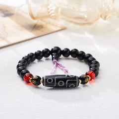 Tibetan Nine-Eye Dzi Bead Black Onyx Bracelet – three-quarter view on gray, dzi bead & mantra details, spiritual jewelry