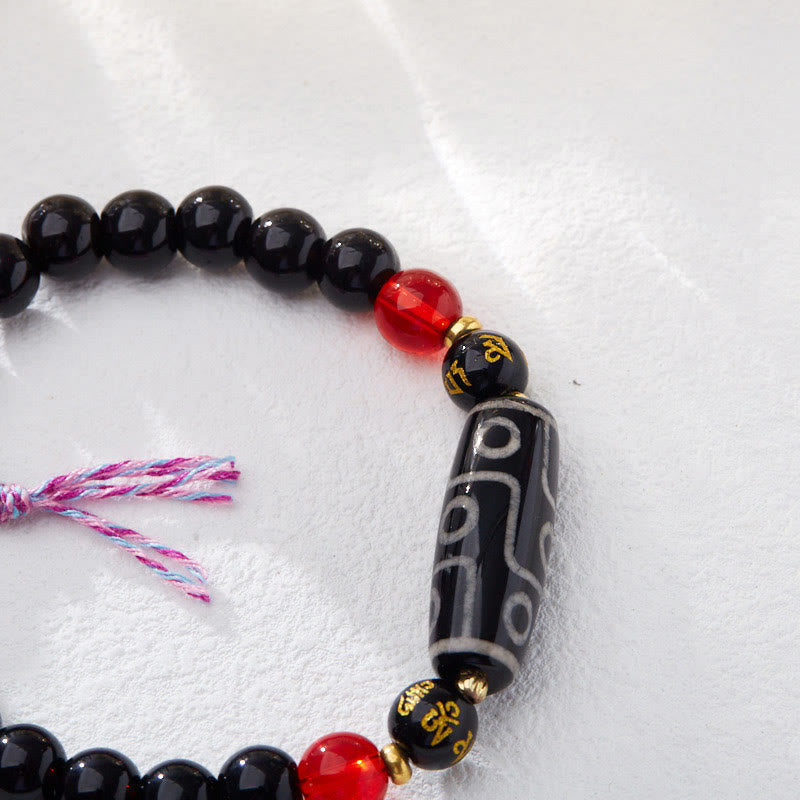 Tibetan Nine-Eye Dzi Bead Black Onyx Bracelet – macro close-up of dzi focal bead & gold mantra inscriptions, dzi jewelry