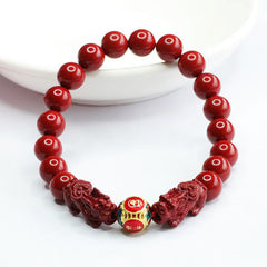 Cinnabar Pixiu Bracelet – vermilion beads with symmetrical pixiu figures and cloisonne center bead on white dish