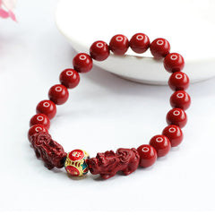 Cinnabar Pixiu Bracelet – close-up of dual pixiu guardians flanking gold enamel wealth bead