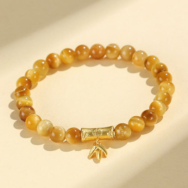 Tiger Eye Fu Bamboo Koi Lotus Bracelet – golden tiger eye beads with gold bamboo and leaf charm on cream, flat lay