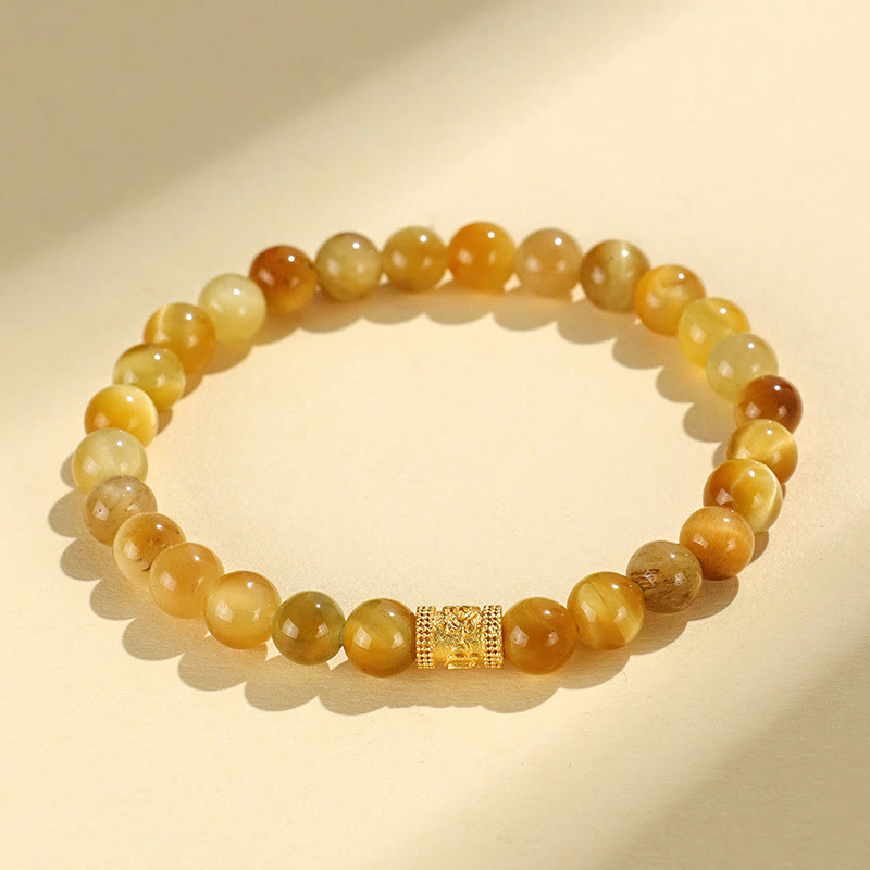 Tiger Eye Fu Bamboo Koi Lotus Bracelet – honey agate beads with ornate gold barrel charm on cream, flat lay