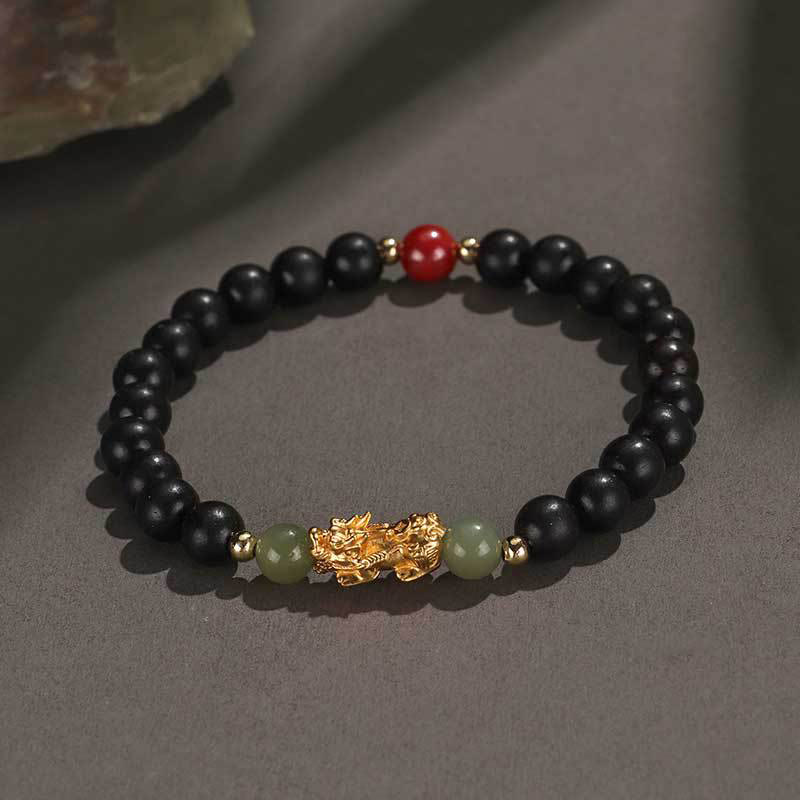 Multi-Wood PiXiu Bracelet – Black ebony wood beads with gold PiXiu, green jade and red bead on gray background