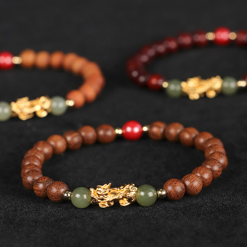Multi-Wood PiXiu Bracelet – Three wood bracelets with gold PiXiu on black fabric, multi-wood collection
