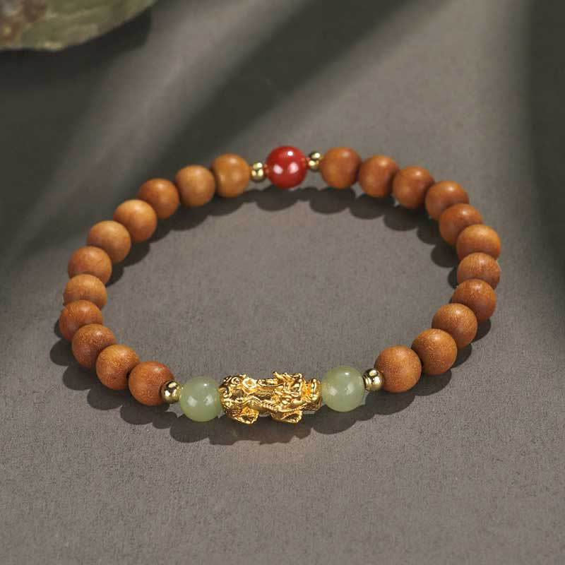 Multi-Wood PiXiu Bracelet – Light brown wood beads with gold PiXiu, green jade and red cinnabar on gray surface