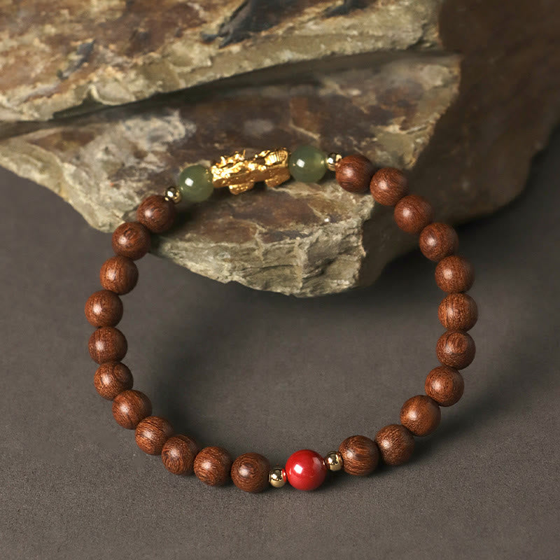 Multi-Wood PiXiu Bracelet – Dark wood bracelet with gold PiXiu and jade beads hanging on textured rock