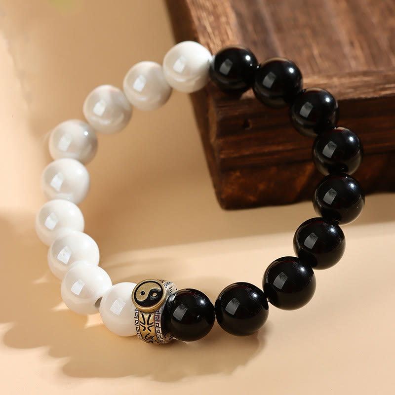 Black Obsidian White Porcelain Yin Yang Bracelet - Yin-yang beaded bracelet with metal charm on beige surface, yin yang bracelet
