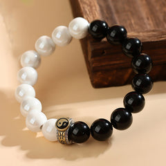 Black Obsidian White Porcelain Yin Yang Bracelet - Yin-yang beaded bracelet with metal charm on beige surface, yin yang bracelet