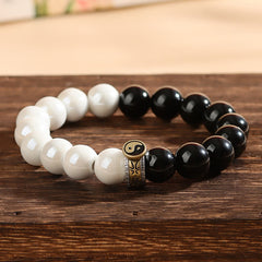 Black Obsidian White Porcelain Yin Yang Bracelet - Curved black and white bead bracelet with yin-yang spacer on wood, obsidian jade bracelet