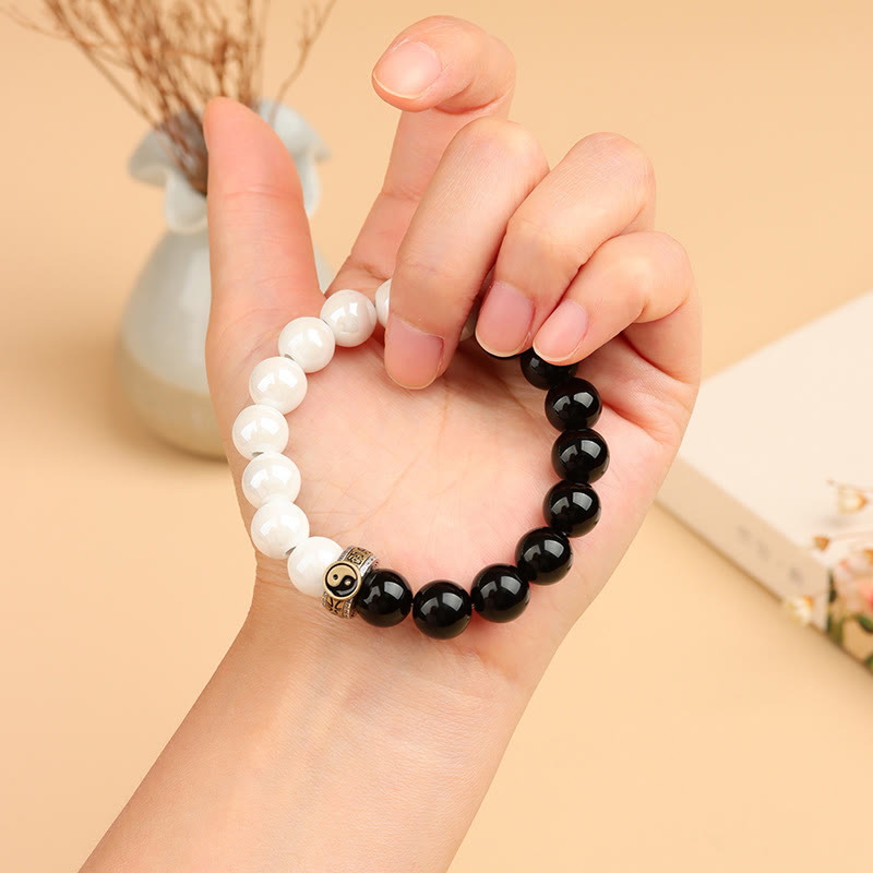 Black Obsidian White Porcelain Yin Yang Bracelet - Yin-yang bracelet worn on hand with dried floral backdrop, beaded healing bracelet