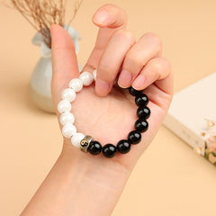 Black Obsidian White Porcelain Yin Yang Bracelet - Yin-yang bracelet worn on hand with dried floral backdrop, beaded healing bracelet