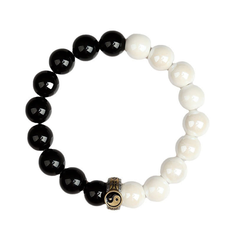 Black Obsidian White Porcelain Yin Yang Bracelet - Circular yin-yang bracelet on white background flat lay, obsidian howlite bracelet