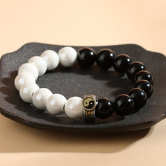 Black Obsidian White Porcelain Yin Yang Bracelet - Circular yin-yang bracelet on dark dish with lotus charm, spiritual balance jewelry