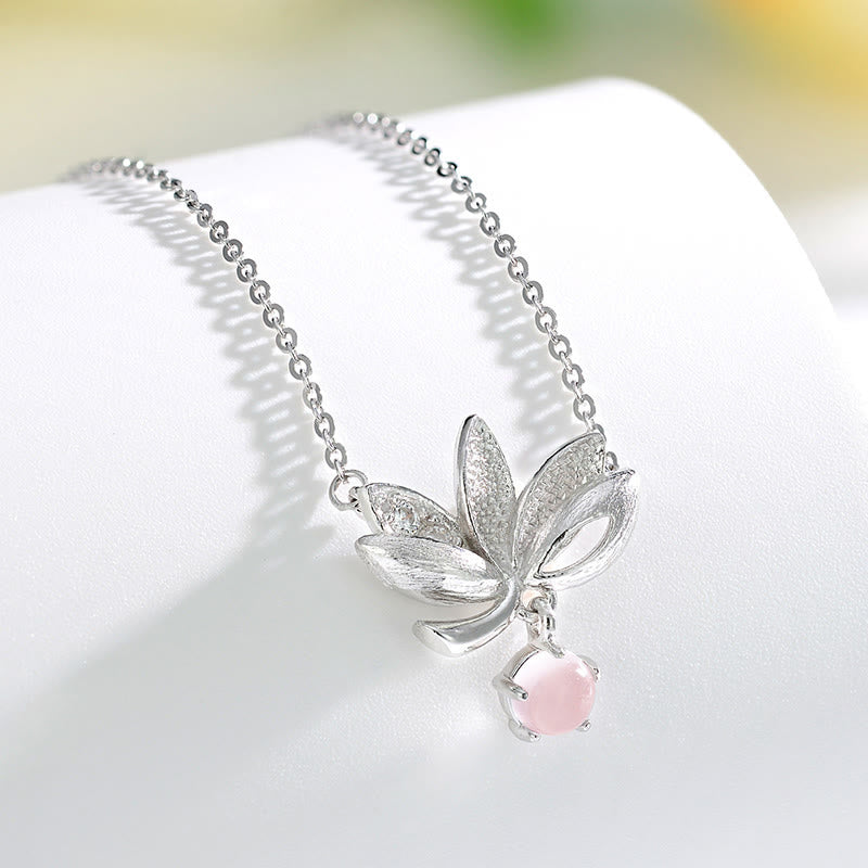 Sterling Silver Lotus Pendant Necklace - chain draped on textured surface with flower, romantic