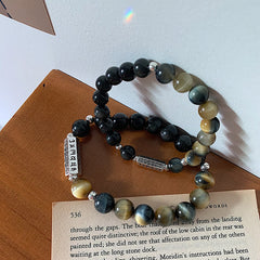 Black Obsidian Tiger Eye Bracelet – Two stacked bracelets with silver charms on wood, tiger eye healing bracelet