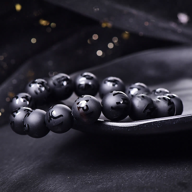 Black Onyx Mantra Bracelet – Spherical black stone beads with engraved symbols on dark surface, spiritual jewelry