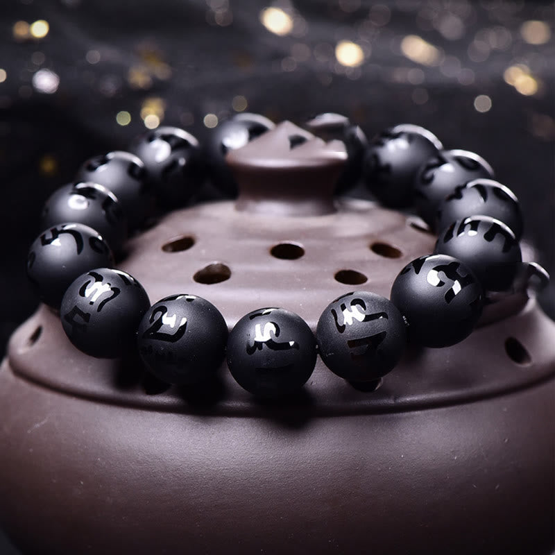 Black Onyx Mantra Bracelet – Obsidian beads with metallic inlay characters on ceramic dish, meditation beads