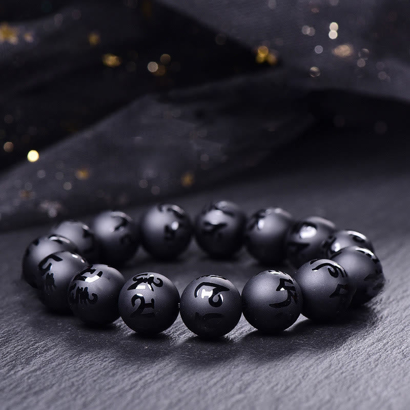Black Onyx Mantra Bracelet – Matte black beads with carved Sanskrit characters on dark stone surface, black onyx bracelet