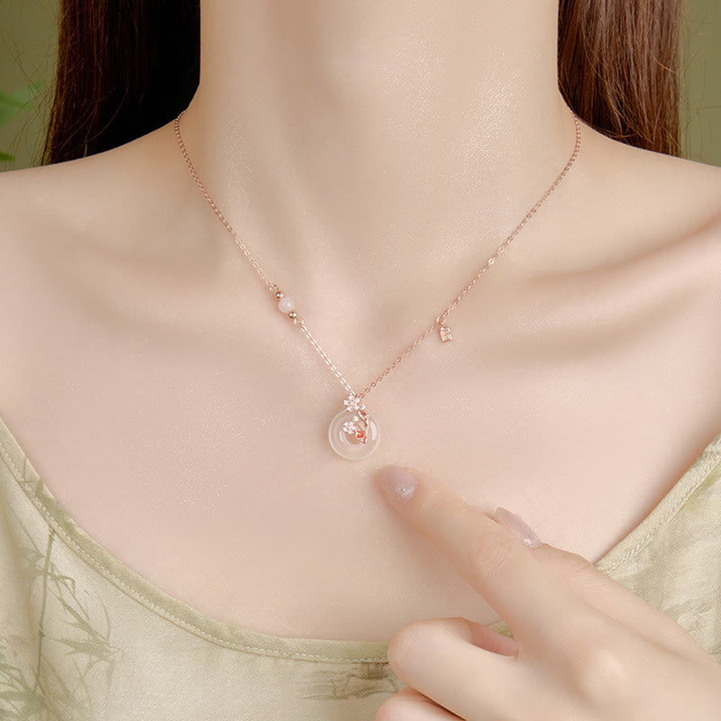 Chalcedony Koi Fish Peace Buckle Necklace – worn on decolletage, finger pointing at floral jade pendant, soft green bg