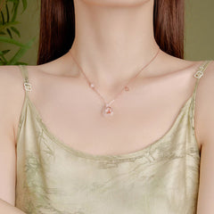 Chalcedony Koi Fish Peace Buckle Necklace – worn close-up, D charm on chain, sage green camisole, olive-green wall