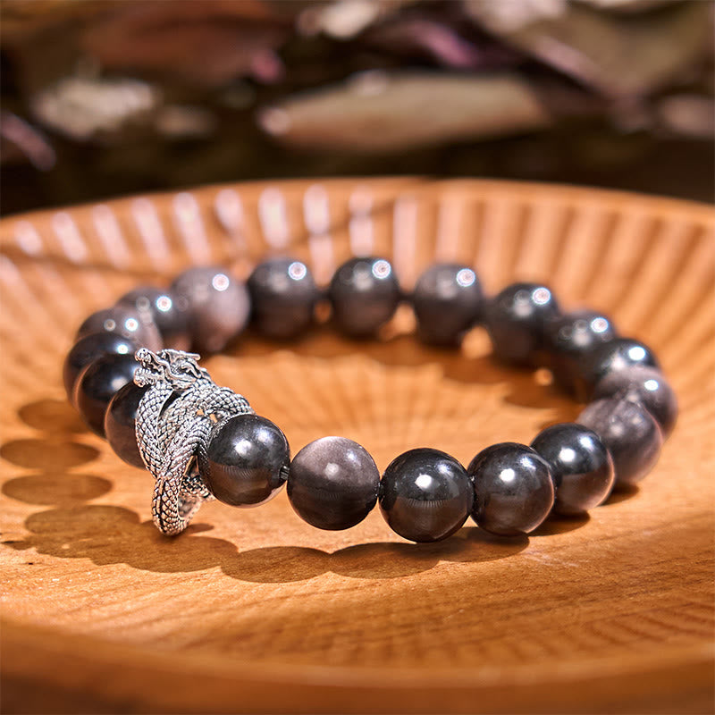 Silver Sheen Obsidian Dragon Protection Bracelet | Strength & Power – obsidian beads with silver dragon on wood, grounding