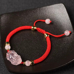 Pink Crystal PiXiu Bracelet – Red cord bracelet with pink crystal charm on black ceramic dish